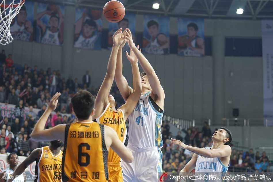 因伤缺阵的王哲林身着便装坐在场边，神情专注地关注着场上局势，时刻准备为队友的精彩表现起身喝彩。