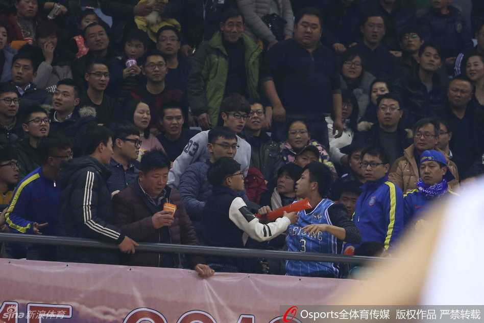 江苏主场大胜北京,球迷误入阵营引发冲突 冲突区域周围的球迷纷纷站立,目光聚焦在扭打的人群上,很多人面露愤怒和不满,有人指着冲突方向大声斥责