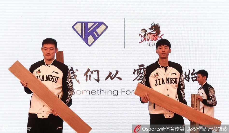 江苏肯帝亚队员常林与助理教练徐强在人民大会堂内轻松交流，身后的红色立柱和金色装饰衬托出这一历史性时刻的氛围。