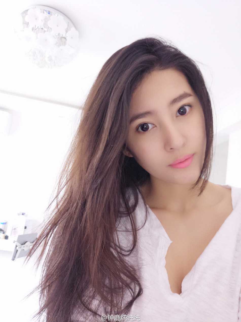 她坐在沙滩上，双手抱膝，温柔地注视着镜头，身后的海浪轻轻拍打着岸边，整个画面洋溢着清新与恬淡的气息，让人移不开眼。