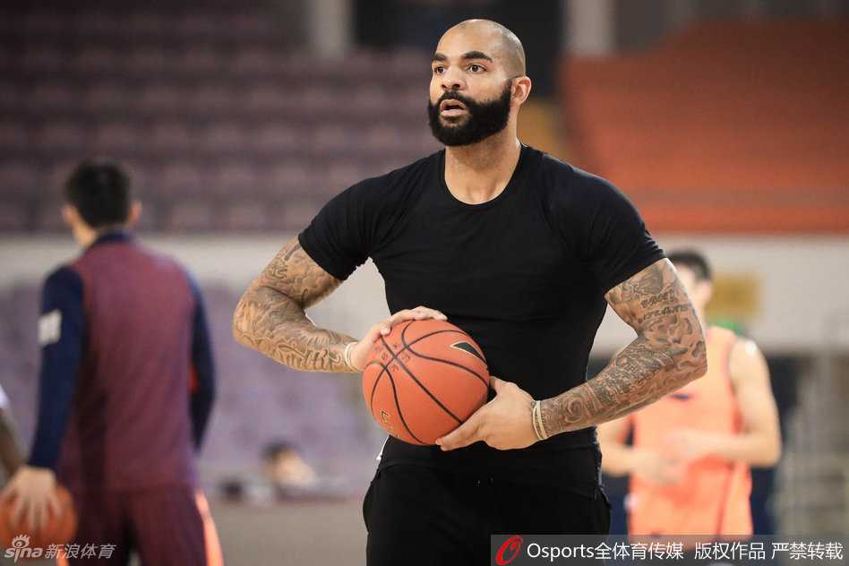 前NBA球星布泽尔神情专注，眉头微锁，在训练场上认真听取教练的战术布置，眼神中透露出不服输的坚韧。