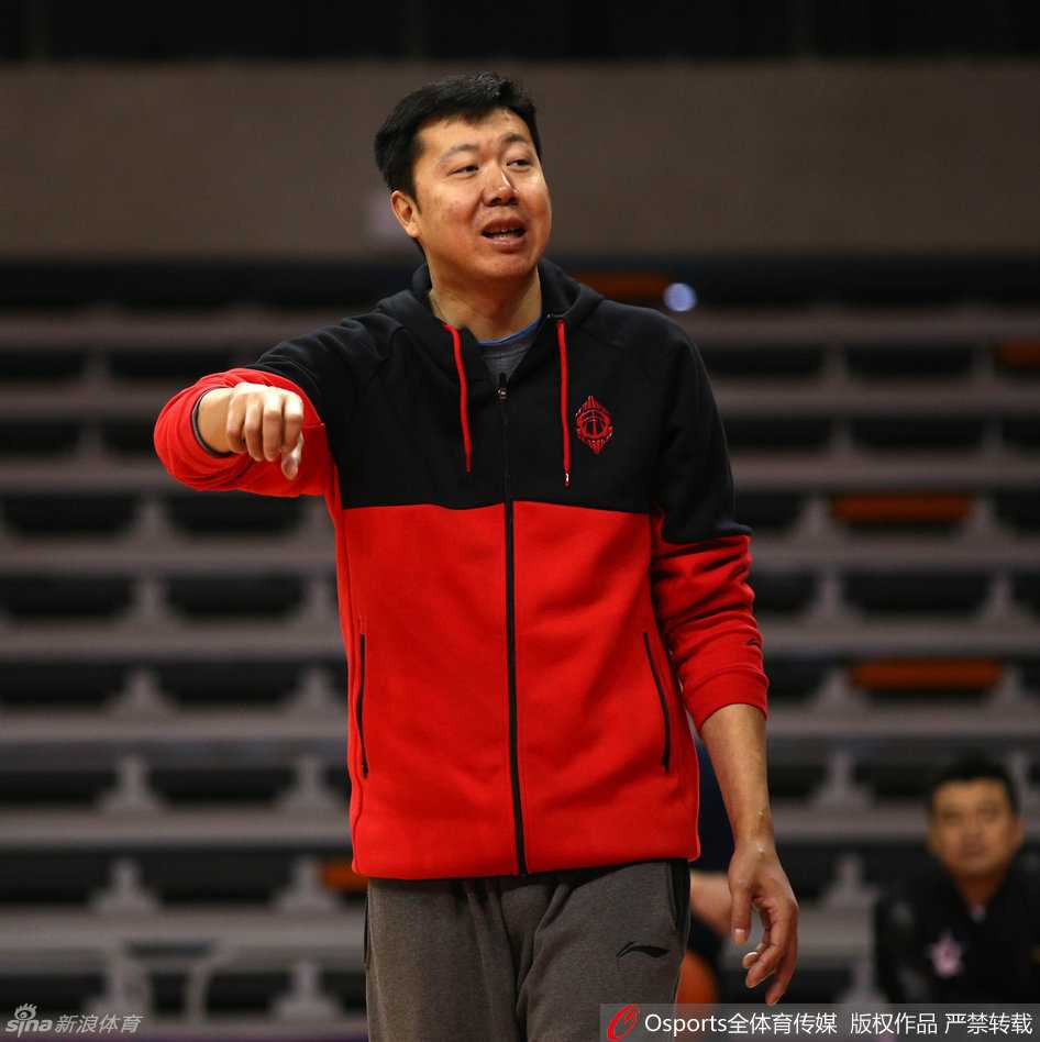 身着黑色训练服的王治郅双手抱胸，目光如炬地盯着场上球员的训练，嘴角挂着他标志性的微笑，仿佛在思考着如何将这些年轻人的天赋捏合成一个整体。