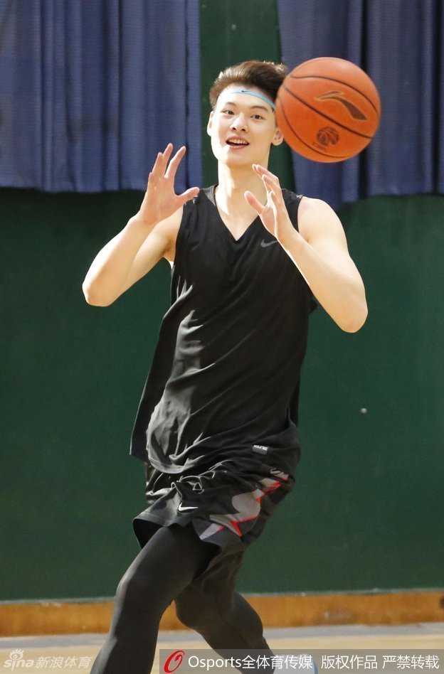 王哲林摘下标志性的蓝色发带，露出被汗水打湿的飘逸长发，眉眼间带着笑意，与队友击掌庆祝训练中的精彩进球。