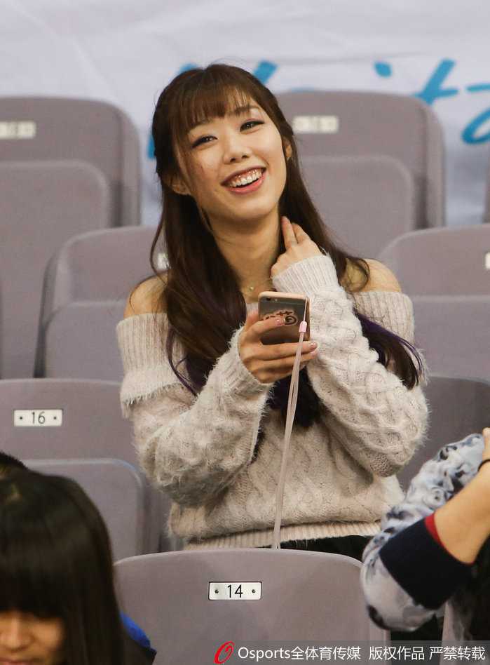 女球迷面对镜头大方比出胜利手势，活力四射，身后是沸腾的北控看台