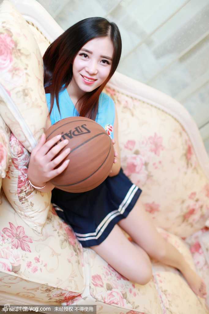 一位篮球宝贝在赛场边定格优美舞姿，学生裙摆随着动作轻盈飘起，她专注的神情与背后模糊的观众席形成对比，凸显了舞台中央的闪耀瞬间。