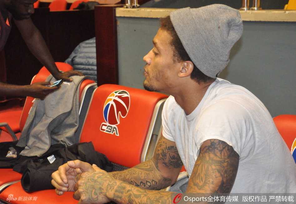 纹身背后的天才榜眼:比斯利的山东记忆与快意人生 迈克尔·比斯利在训练中突然搞怪,用球衣蒙头扮鬼脸,一旁球鞋显眼,严肃的训练场瞬间充满欢乐气氛。