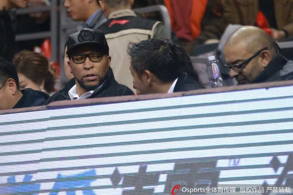 比赛暂停期间，马里昂侧身与身旁的一位工作人员交谈，他眉头微蹙，似乎正在交流着对场上球员表现的看法，背景是喧嚣的球场。