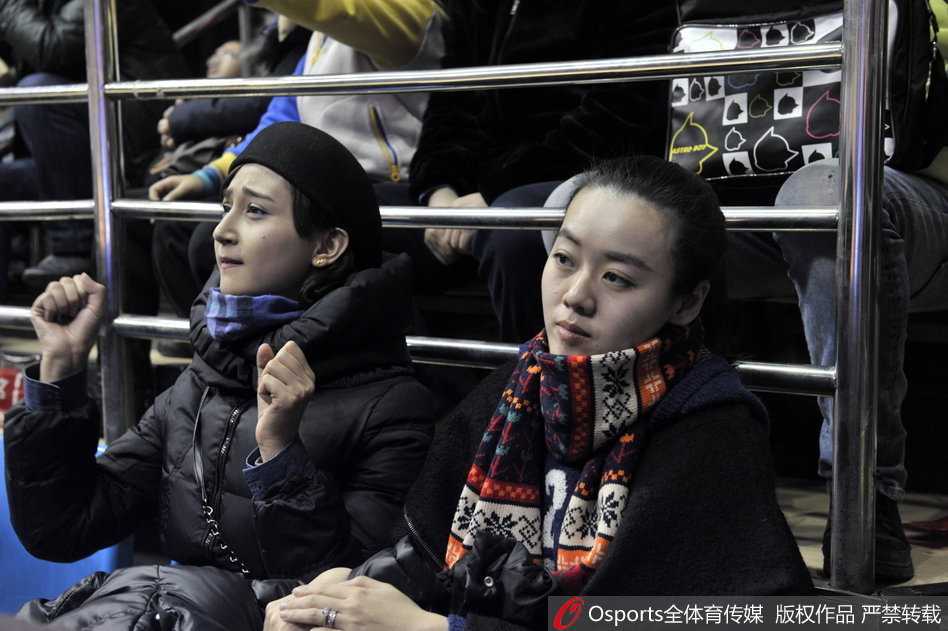 杨思雨穿着时尚的棒球服，露出修长的双腿，在人群中格外抢眼，她正对着镜头比出胜利的手势，为男友翟晓川加油打气