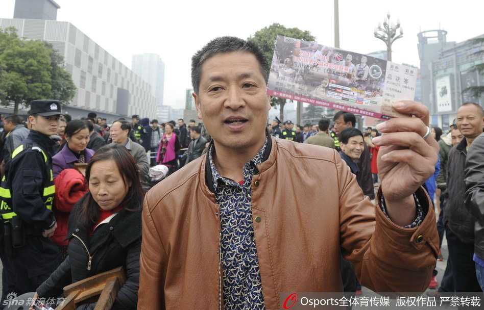 热闹非凡的排队人群中，一对情侣球迷依偎在一起，共享一张刚买到的球票。他们的脸上没有丝毫困意，只有对即将到来的巅峰对决的无限向往。