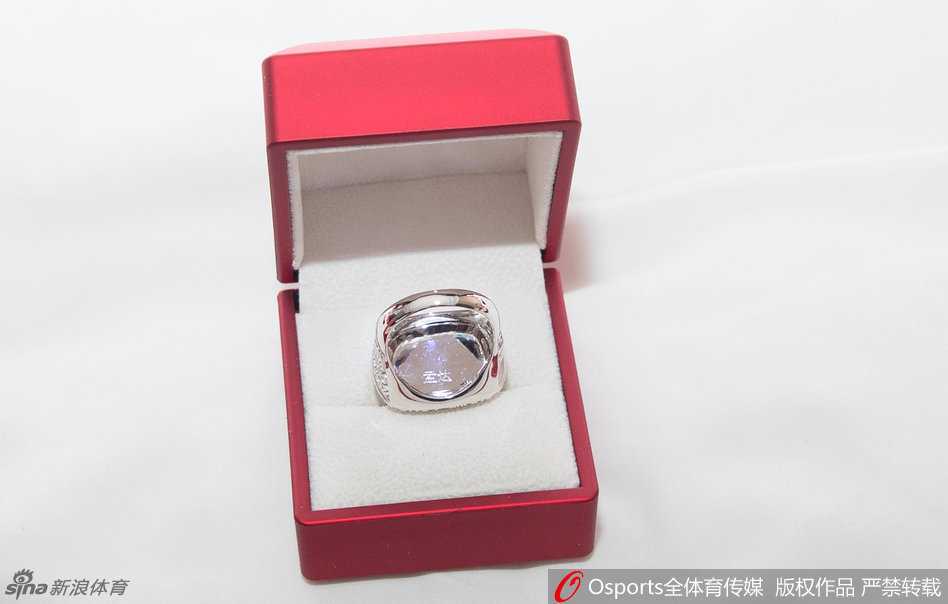 球队主帅杨学增指导微笑着站在队员中间，他手中同样拿着一枚属于自己的总冠军戒指，身后是看台上挥舞着旗帜、欢呼雀跃的四川球迷