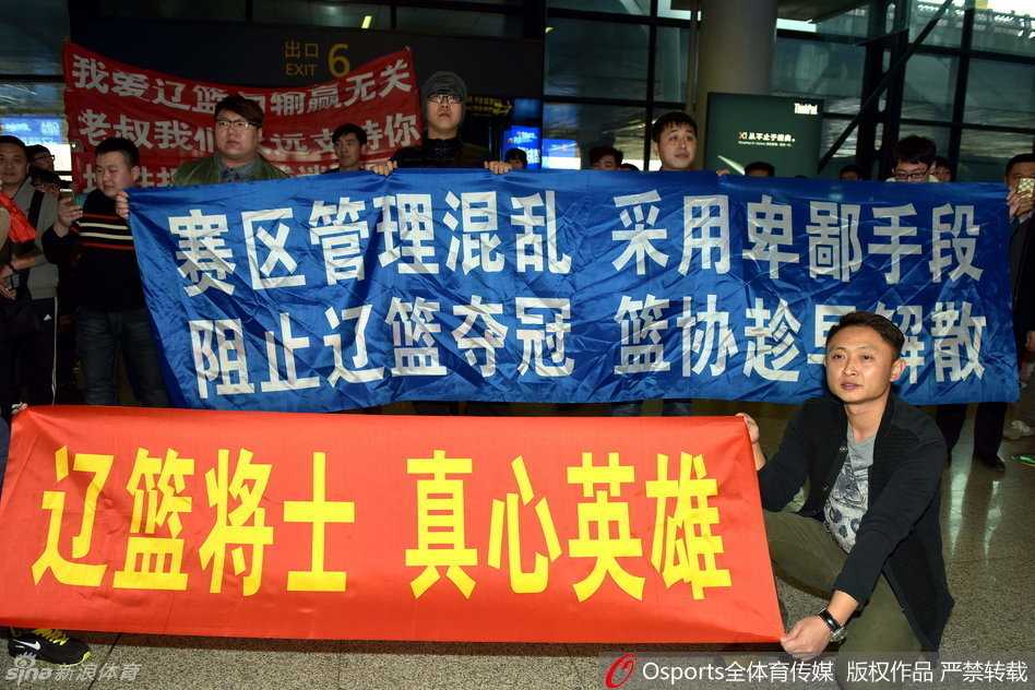 人山人海的接机大厅里，一名辽宁男篮球迷眼含热泪，高高举起写着“还我公平”的白色纸牌，眼神中充满委屈与坚定。