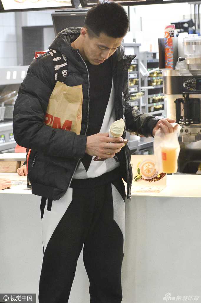 廉明被热情的球迷团团围住，他倚靠着机场的柱子，专注地在伸过来的各种物品上签名，脸上带着憨厚的笑容。