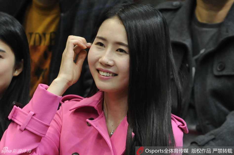 一位身穿白色上衣的辽宁美女球迷，在看台上露出温婉的笑容，气质清新脱俗