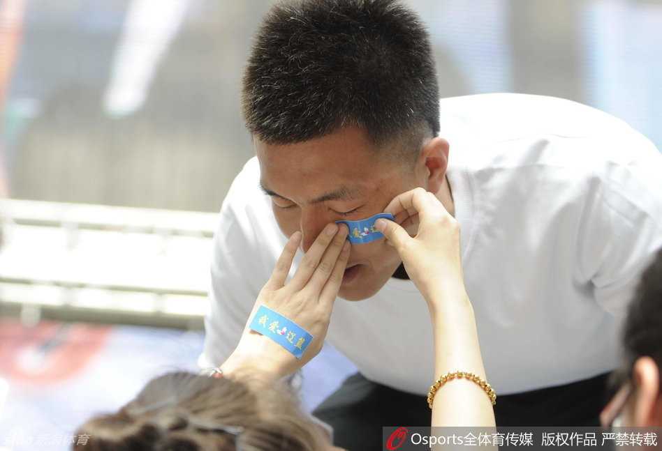 郭艾伦贴心地在脸上贴上招牌胶布，弯下腰与女球迷甜蜜自拍，眼神里满是宠溺。