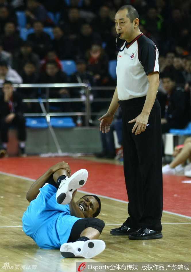 特尔费尔痛苦地倒在地上，双手紧捂受伤的脚踝，面部表情因剧痛而扭曲，身边的队友和对手都焦急地围拢过来，向场边的队医紧急示意。