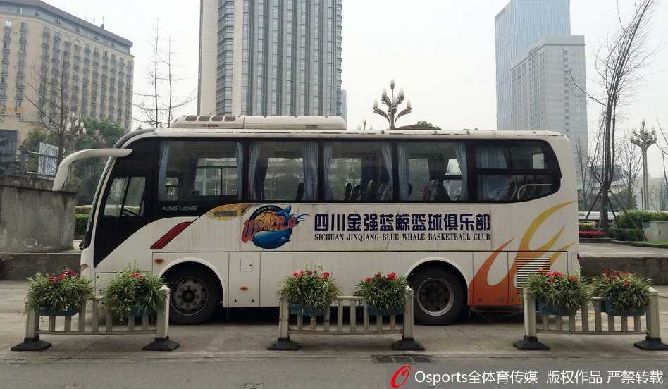 锦江宾馆门前的寂静与喧嚣:回溯CBA总决赛上的那一夜 空旷的酒店门前,一辆喷涂着‘四川队’标识的蓝白大巴车孤零零地停靠在路边,车身反射着午后惨白的阳光,车内空无一人,仿佛在诉说着赛事停摆的紧张与不确定。