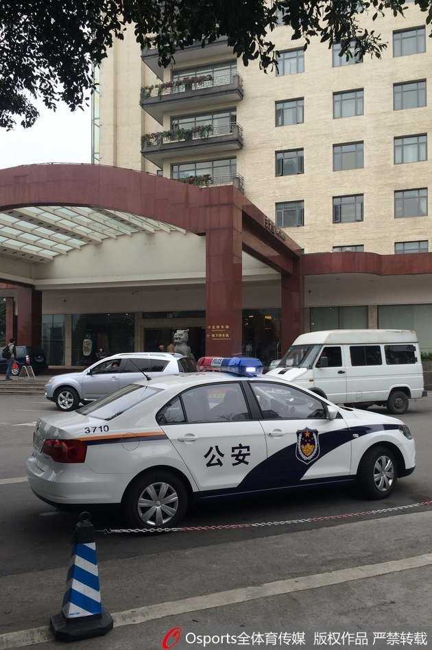 锦江宾馆门前的寂静与喧嚣:回溯CBA总决赛上的那一夜 灰暗的天色下,数辆警车闪烁着红蓝警灯,整齐排列在锦江宾馆门前,身穿黄色反光背心的警察来回踱步警戒,酒店旋转门内空无一人,折射出大战前夕令人窒息的肃杀氛围。