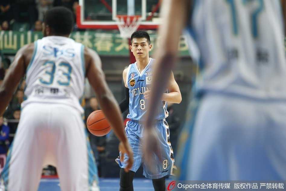 北京首钢球员吉喆张开双臂全力防守，福建王哲林持球伺机而动