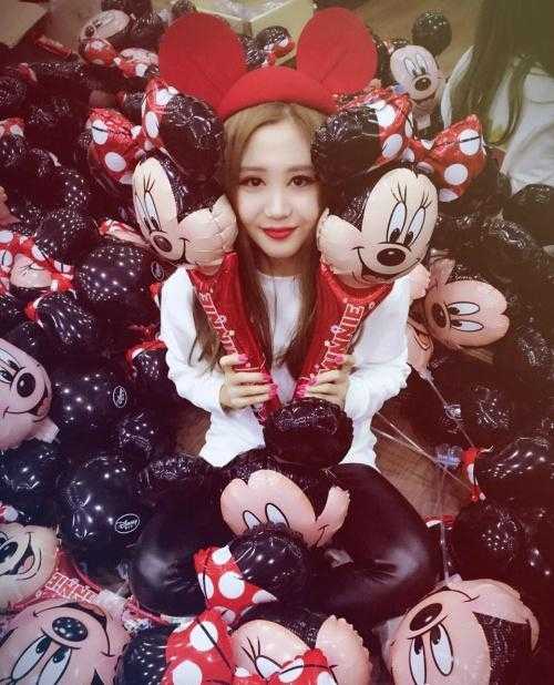 这位啦啦队员似乎正在后台休息区，她身穿一件简约的灰色上衣，面带淡淡的微笑，眼神清澈明亮，整个画面给人一种岁月静好的温馨感，与赛场的喧闹形成鲜明对比。