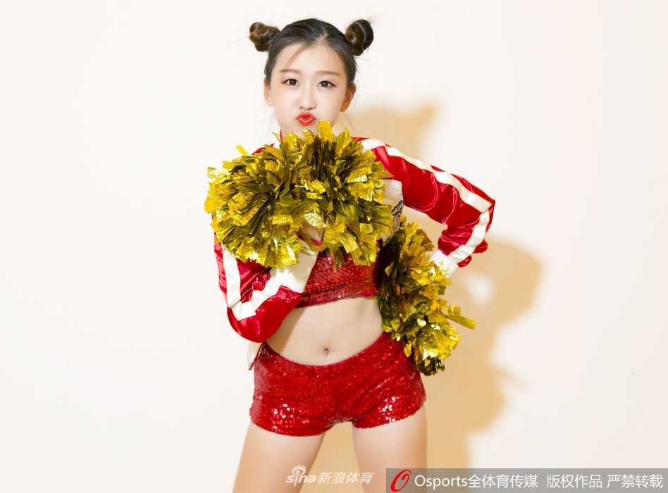 身着活力黄色短裙的啦啦宝贝，在赛场边定格了一个俏皮的瞬间。她轻轻眨眼，双手比出可爱的姿势，仿佛在用无声的语言为场上的球员加油鼓劲。