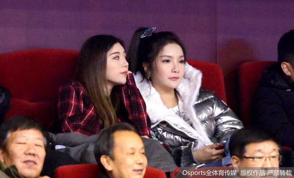 终场哨响，山东队获胜，两位闺蜜在看台上激动地拥抱在一起，喜悦之情溢于言表，身后是庆祝胜利的球迷海洋