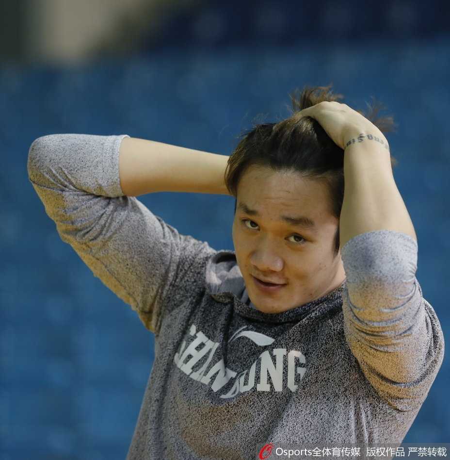 小丁身穿便装在街头，回头看向镜头的瞬间，表情带着一丝懵懂和天然呆。