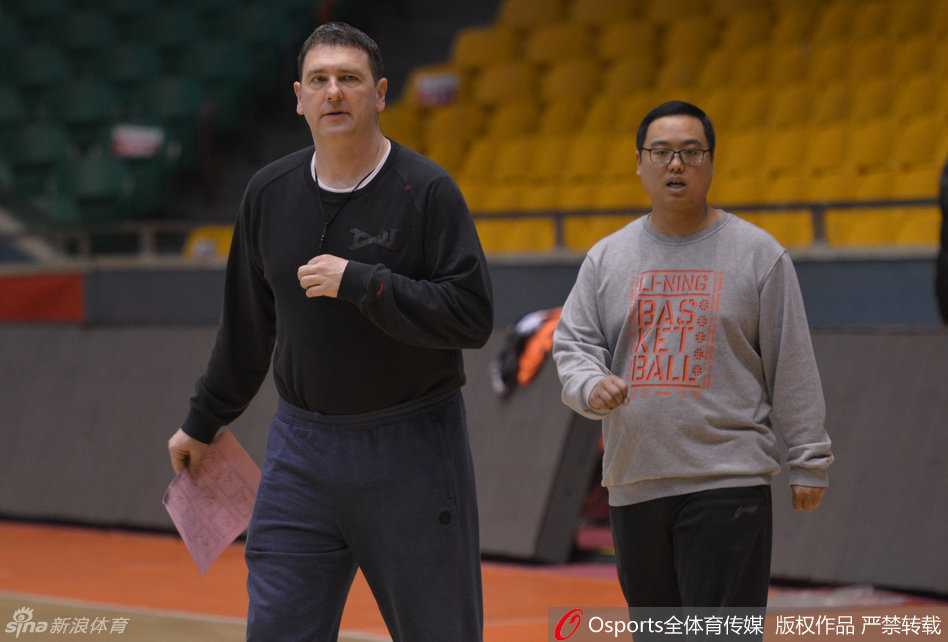 训练场上，一名队医正蹲在地上，神情专注地为坐在凳子上的球员进行腿部包扎，旁边的队友们投来关切的目光。