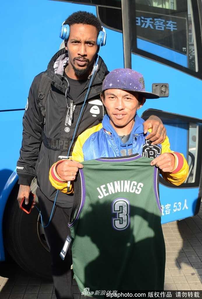 酒店大堂内，路易斯·斯科拉被众多球迷层层包围，这位前火箭队名宿微微弯腰，侧耳倾听一位小球迷的请求，脸上的笑容如同他名字“钻石”般温暖而璀璨。