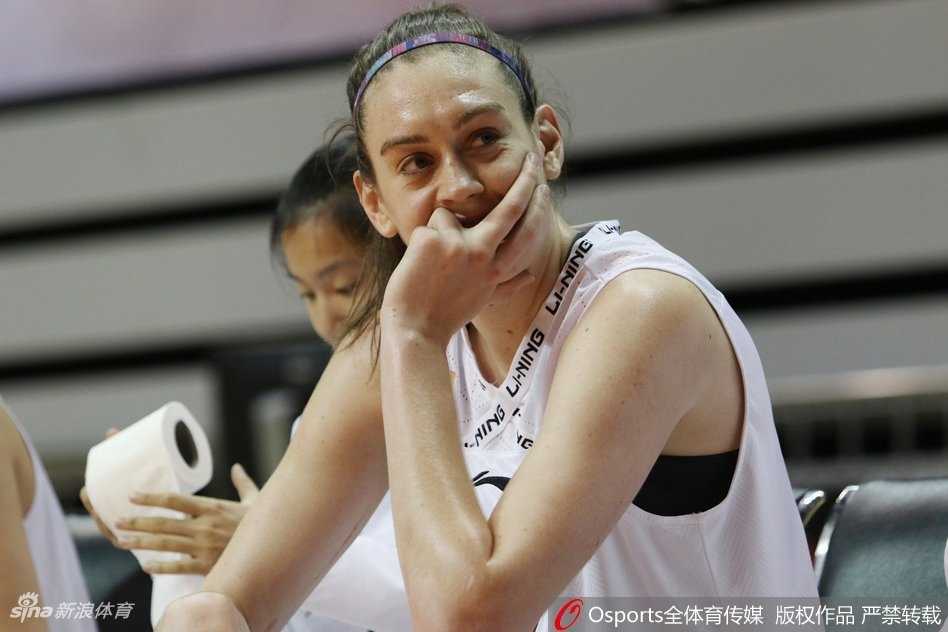 看台上热情的主队球迷挥舞旗帜和充气棒，齐声呐喊为上海女篮助威