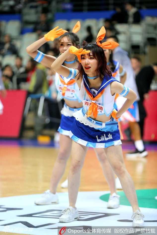 一位篮球宝贝扎着双马尾，身着蓝白相间的应援裙，在球场中央随着音乐轻盈跃起，甜美的笑容仿佛从动漫中走出的元气少女。