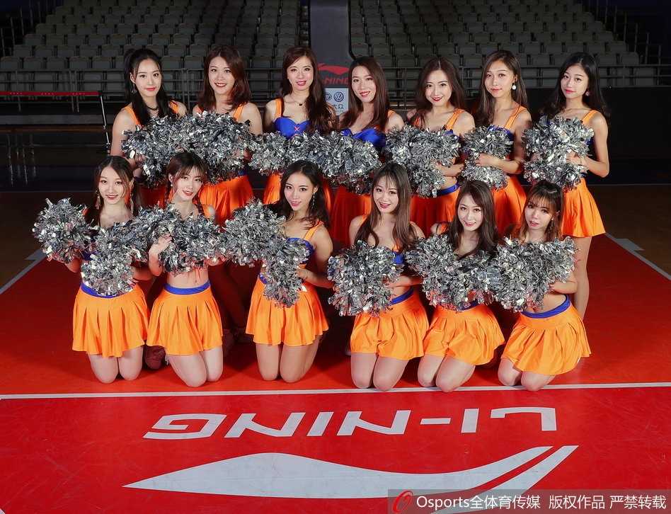 上海IDANCE啦啦队宝贝们身着亮橙色表演服，在球场上整齐列队，她们面带灿烂微笑，双手高举挥舞，瞬间点燃全场热情。