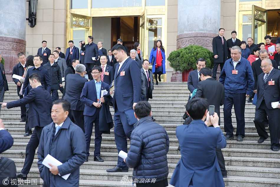 从人民大会堂走出的王励勤，面带微笑向远处注视，胸前佩戴着鲜红的出席证，尽管已退役多年，但身上依然保持着运动员特有的挺拔与干练，透出一股为国履职的担当。