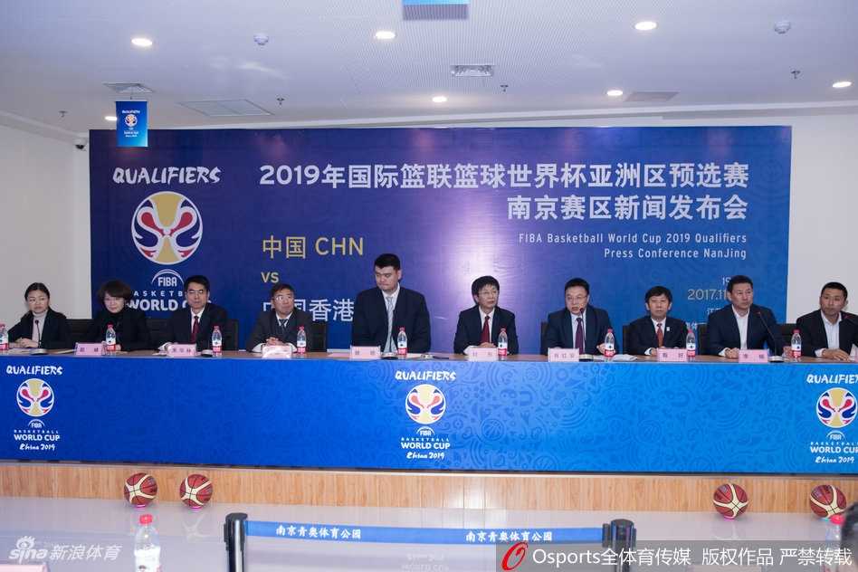 中国男篮红队主帅李楠在发布会上神情专注地聆听提问，身穿的国家队外套上绣着的五星红旗格外醒目，仿佛在无声地诉说着肩上的重担。