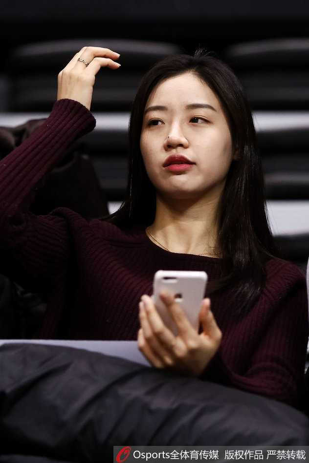 一位面容清秀的中国女球迷，身披鲜艳的五星红旗，眼神中满含对胜利的渴望，静静地坐在看台上，仿佛在默默祈祷。