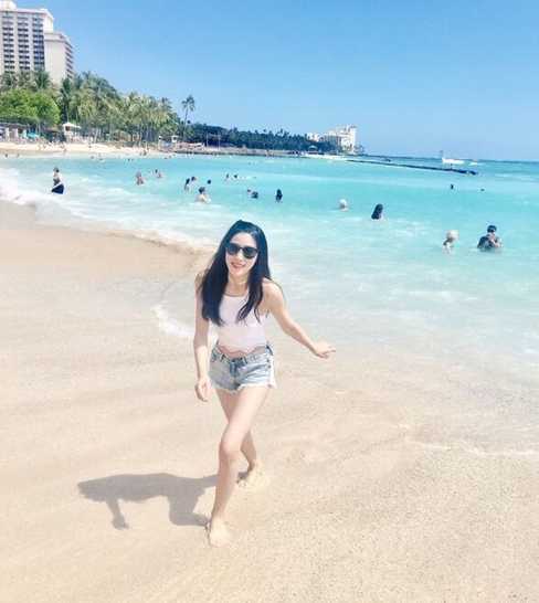 一位空姐漫步于金色沙滩，及膝的裙摆被海风轻轻撩起，修长笔直的双腿在阳光下泛着健康的光泽，她回眸一笑，身后是层叠的浪花与无尽的蔚蓝。