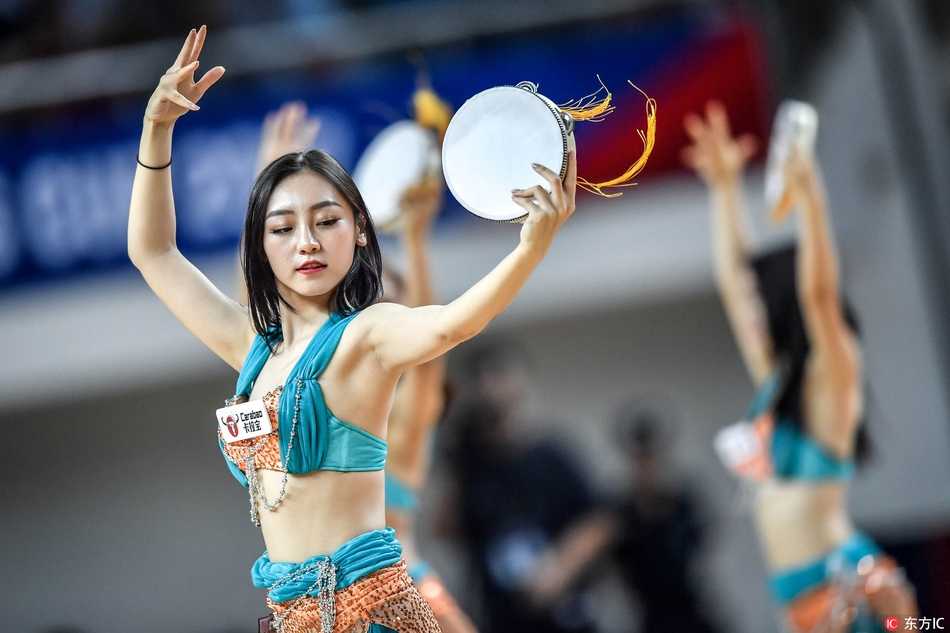 清凉装扮的宝贝们全神贯注地演奏着手鼓，统一的红色着装如同火焰，与赛场上的激烈对抗相得益彰，成为看台上一道移动的风景线。