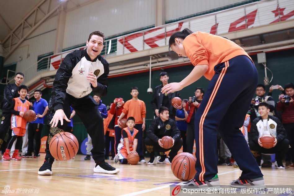 刘炜与弗雷戴特两位老将新星同框，正在专注地为篮球训练营的小球员做标准运球动作示范