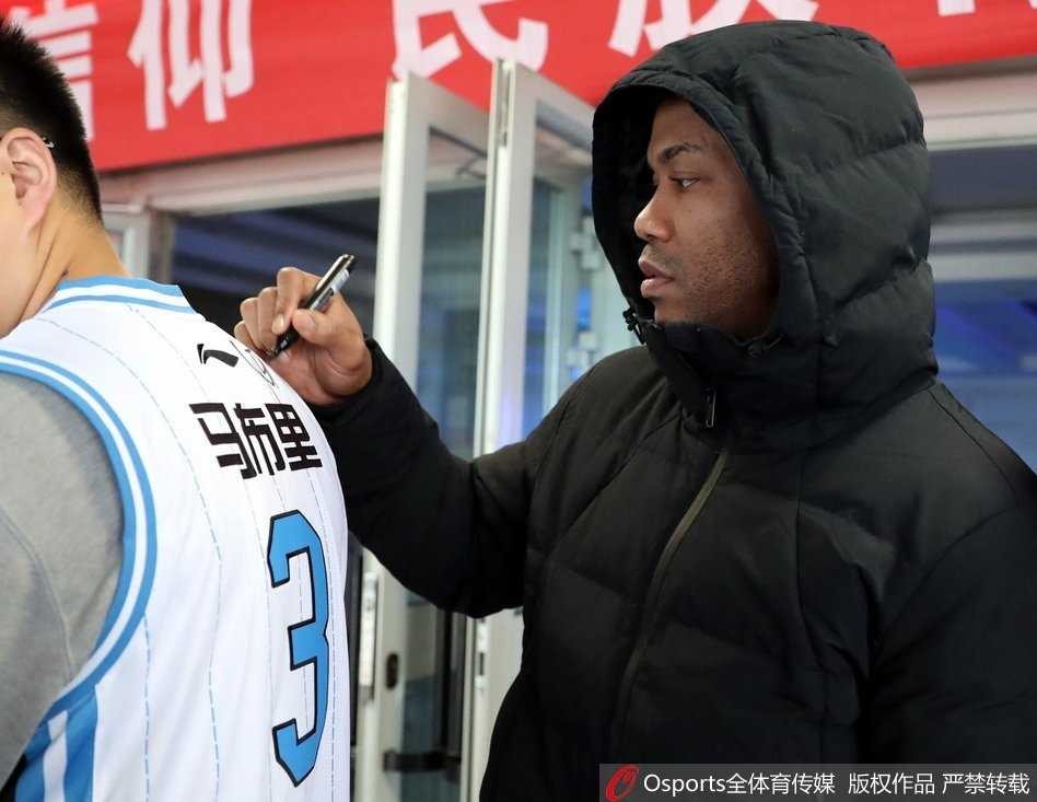 在洒满阳光的奥体中心篮球馆内，刚刚结束高强度训练的马布里，额头上还挂着汗珠，他弯下腰，神情专注而温和，正在一件白色的北京首钢3号球衣上为激动的粉丝签名，眼神里满是对这座城市的眷恋。