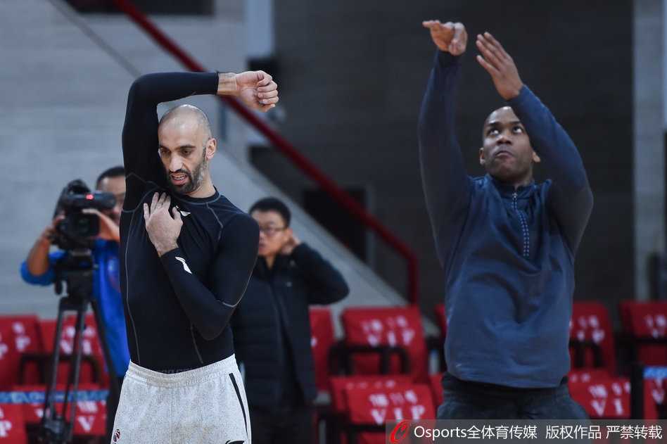 马布里和阿巴斯这对北控双核，正在训练师的带领下全神贯注地进行健身操热身，每一个伸展动作都充满了力量感。