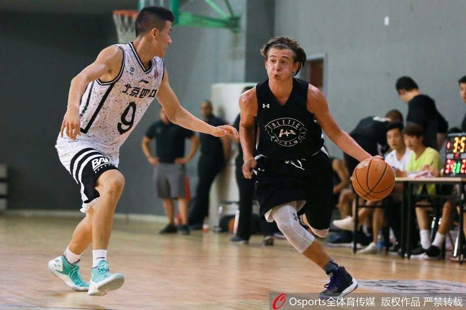 京城篮坛青春对决:北京四中激战美国联队七分之差 北京四中后卫如尖刀般刺破美国队的防线,他顶着防守人强行上篮,身体在空中对抗后失去平衡,却依然将球稳稳送入篮筐,瞬间点燃全场激情。