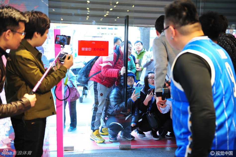 方硕低头弯腰，正在一张海报上认真地签下自己的名字，周围伸过来无数只手和签名笔，记录下这珍贵的零距离接触瞬间