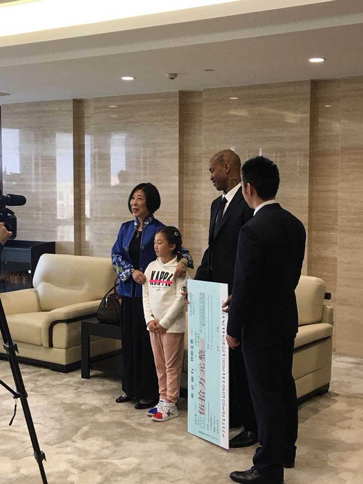 在摆满球员背包的球队休息室里，张阿姨被北控球员们围在中间，大家脸上都洋溢着惊喜与感激的笑容，向她鼓掌致意，场面温馨热烈。