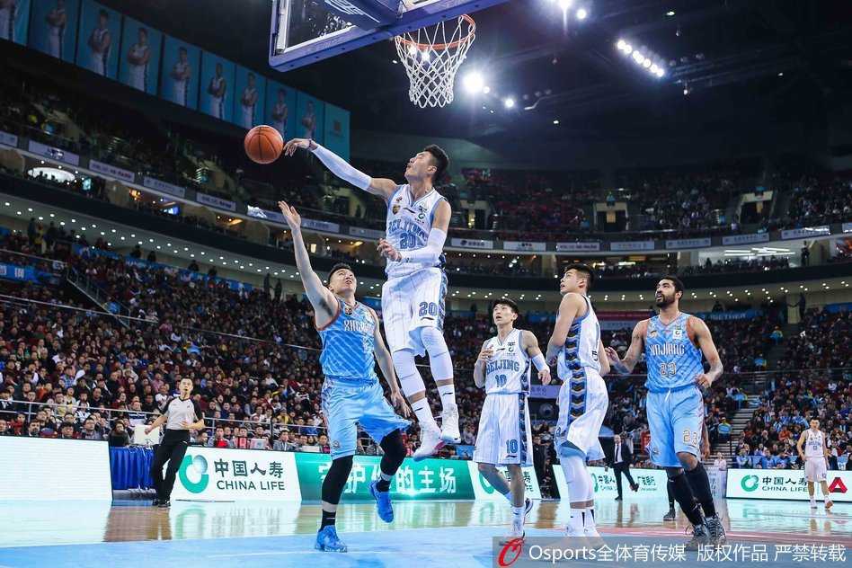 北京外援汉密尔顿在新疆内线群中高高跃起，单手抓球试图补扣，展现出惊人的臂展和制空权。