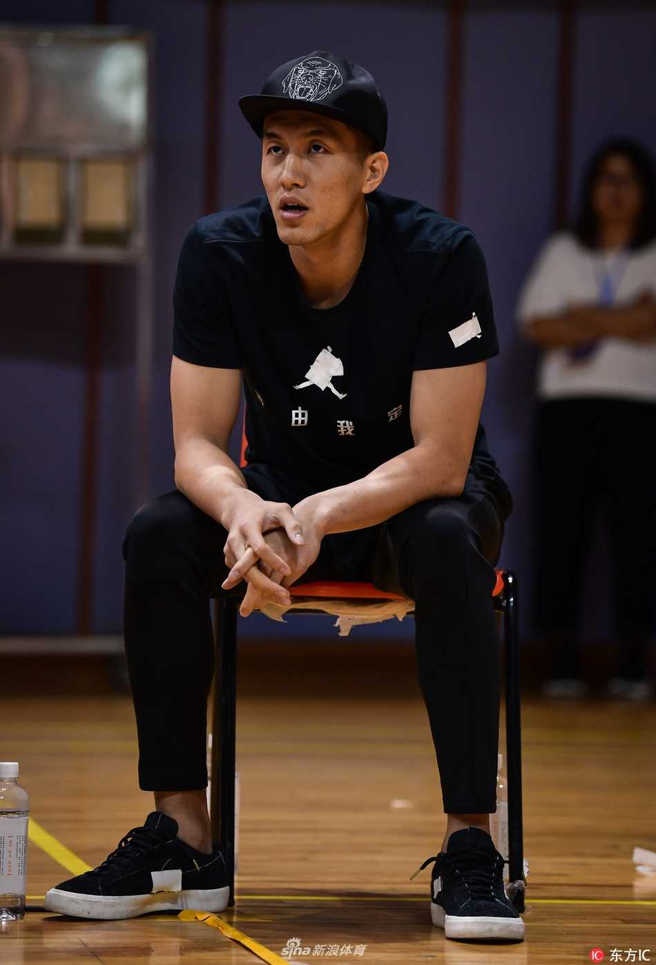 郭艾伦在场边为队友的精彩表现鼓掌喝彩，眼神中充满鼓励，身后的赵继伟也在关注着场内动态