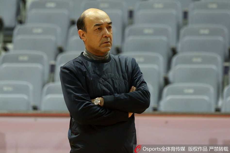 八一全队在进行赛前最后的热身拉伸，球员们围成一圈，手臂搭着彼此的肩膀，王治郅站在圈中做最后的动员，年轻的面孔上写满了对比赛的渴望和铁军的凝聚力。