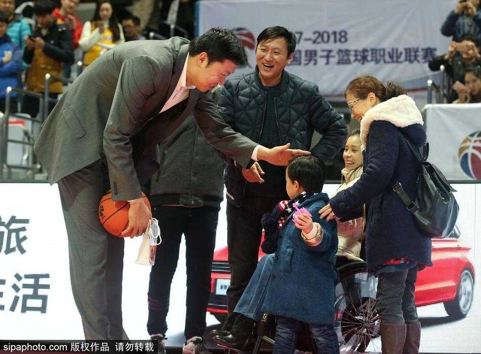 王治郅面带标志性的憨厚笑容，弯下高大身躯与轮椅上的桑兰交谈，两人眼神交汇间满是老友重逢的亲切与关怀。