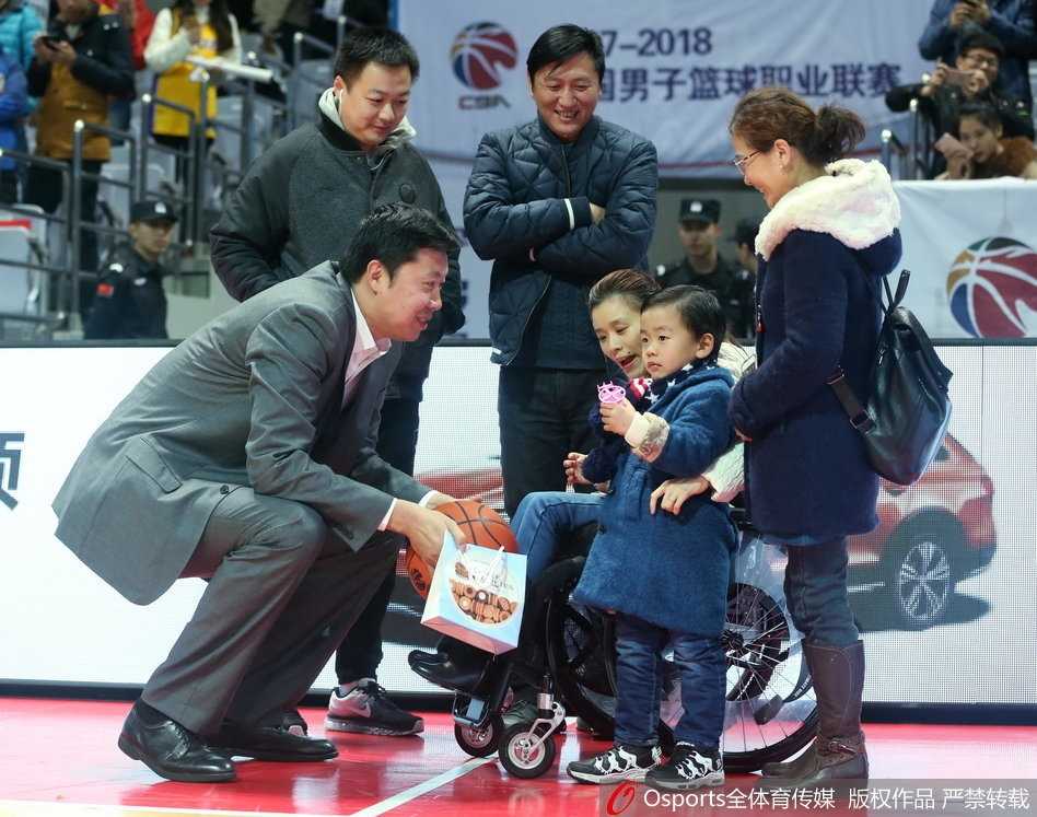 王治郅站在场边，正在给八一队的年轻球员布置战术，他的表情专注而认真，手里比划着跑位路线，身后的球馆灯光将他的身影拉得很长。