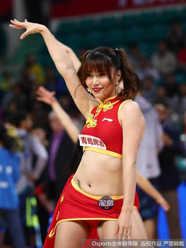 镜头拉近，这位篮球宝贝脸颊上贴着亮片，她轻抿嘴唇，眼神中透露出专注与灵动，身后的队友身影虚化，更凸显了她此刻的迷人神态。