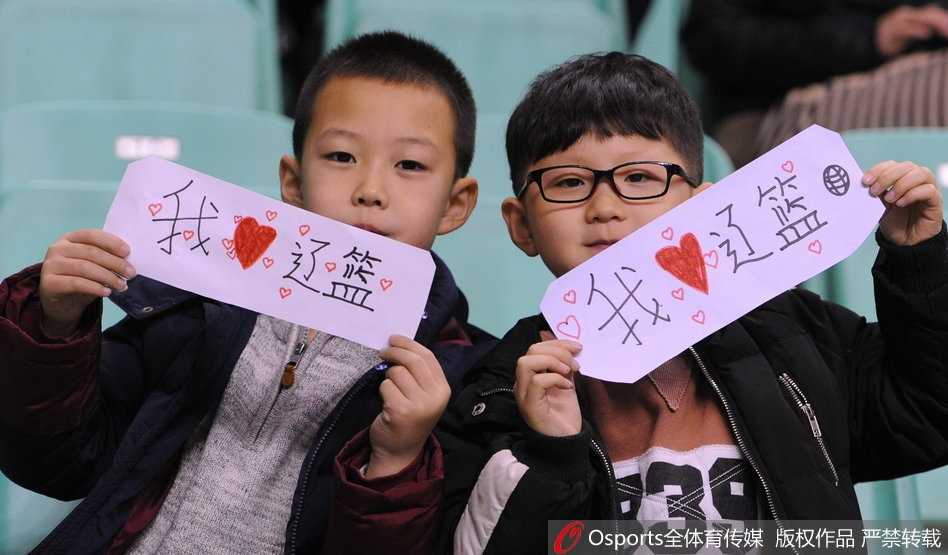 全景镜头下，辽宁体育馆内座无虚席，球迷们身穿统一的白色助威服，汇聚成一片白色的浪潮。场地中央，身穿白色球衣的辽宁队员正与身穿深色球衣的福建队员激烈拼抢，现场气氛紧张而热烈。