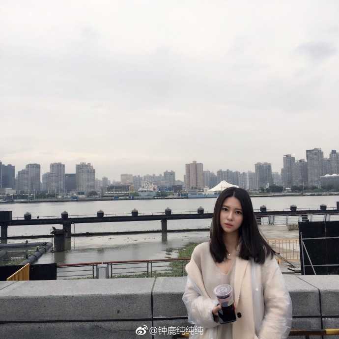 钟鹿纯身穿一袭纯白连衣裙，置身于简洁背景下，眼神清澈明亮，宛如童话中走出的温柔公主，展现出纯净典雅的东方美。